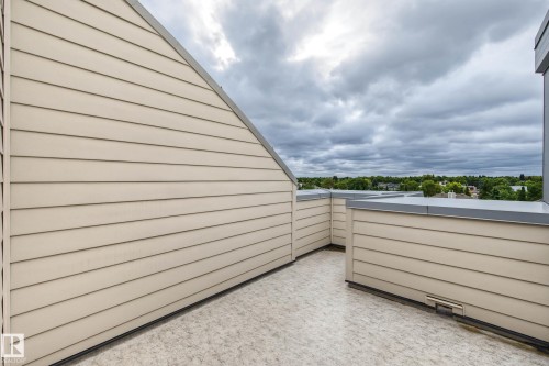 Rooftop terrace with horizontal siding, protective wall capping, and a textured floor surface - #505 7839 96 St Nw, Edmonton, AB 