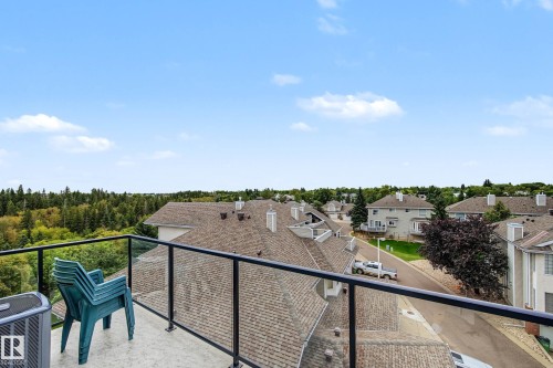 Balcony featuring glass panel railing, concrete flooring, and surrounding neighborhood rooftops - #505 7839 96 St Nw, Edmonton, AB 