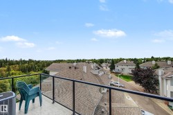 Balcony featuring glass panel railing, concrete flooring, and surrounding neighborhood rooftops - 