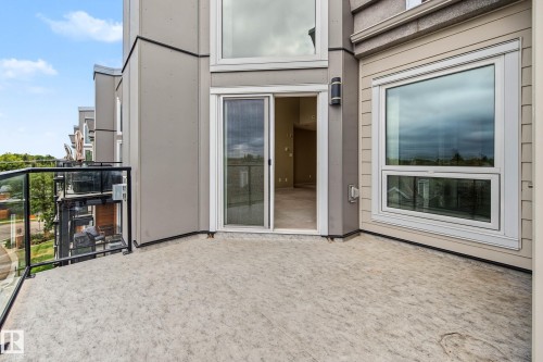 Exterior balcony with a glass railing, concrete flooring, and an adjacent sliding glass door - #505 7839 96 St Nw, Edmonton, AB 