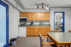 Compact kitchenette featuring wood cabinetry, laminate countertops, a built-in microwave, and a mini-refrigerator - 