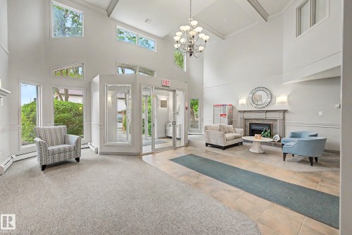 Vaulted ceiling with a chandelier, varied window configurations, built-in fireplace, and tile flooring - #505 7839 96 St Nw, Edmonton, AB 