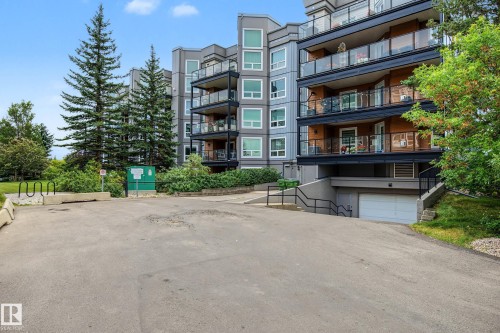 Multi-story building featuring balconies with glass railings, an integrated garage, and mature landscaping - #505 7839 96 St Nw, Edmonton, AB 