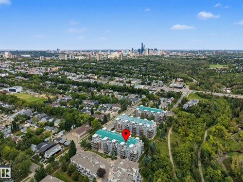 Building exterior with multiple balconies and a light blue roof, surrounded by mature trees and residential areas - #505 7839 96 St Nw, Edmonton, AB 