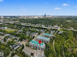 Building exterior with multiple balconies and a light blue roof, surrounded by mature trees and residential areas - 