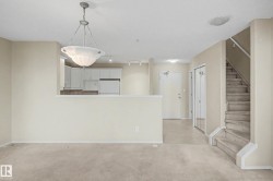 Open-concept living space with a kitchen pass-through, neutral wall tones, and overhead lighting - 