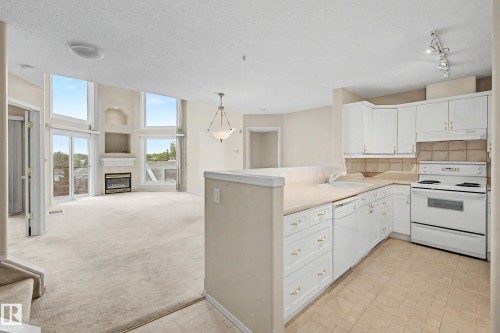 Open-concept living area with a fireplace and large windows - #505 7839 96 St Nw, Edmonton, AB 