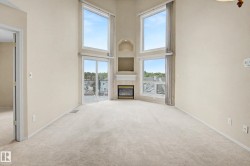 High ceilings with angular window designs, built-in fireplace with mantel, sliding glass door, and neutral-toned carpeting - 