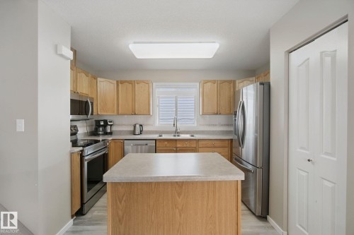 Kitchen with wood-finish cabinetry, stainless steel appliances, central island with countertop, and wood-finish flooring - 13912 156 Avenue Nw, Edmonton, AB 