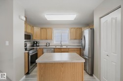 Kitchen with wood-finish cabinetry, stainless steel appliances, central island with countertop, and wood-finish flooring - 