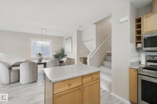 Kitchen island with wood-finish cabinetry and light countertop - 13912 156 Avenue Nw, Edmonton, AB 