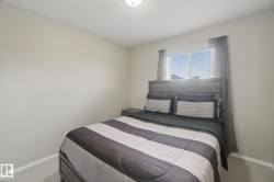 Neutral wall paint, ceiling-mounted light fixture, window with blinds, and light-toned carpeting - 