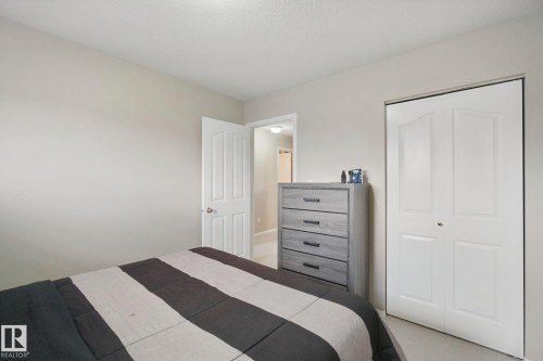 Light-colored wall paint with carpet flooring, featuring a paneled interior door and a bi-fold closet door - 13912 156 Avenue Nw, Edmonton, AB 