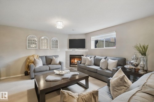 Corner fireplace with tile surround, a large window, and recessed lighting - 13912 156 Avenue Nw, Edmonton, AB 
