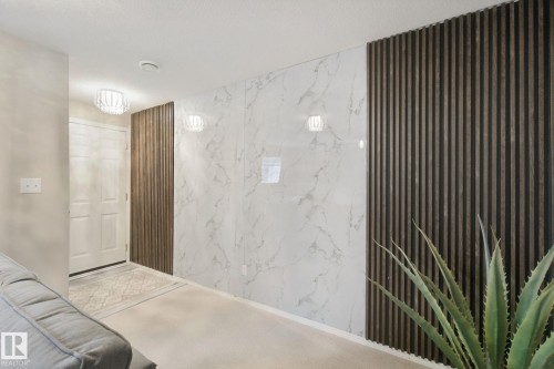 Entryway featuring a white paneled door, decorative ceiling light fixture, accent wall with vertical wood paneling, and white wall panels with grey veining - 13912 156 Avenue Nw, Edmonton, AB 