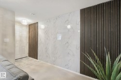 Entryway featuring a white paneled door, decorative ceiling light fixture, accent wall with vertical wood paneling, and white wall panels with grey veining - 