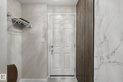 White panel door with brass hardware, wall-mounted wire shelving, and wood-slat accent wall - 13912 156 Avenue Nw, Edmonton, AB 