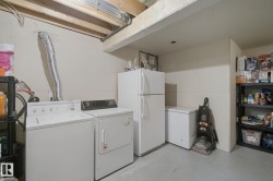 Laundry area featuring a washer and dryer, exposed ceiling joists, and a concrete floor - 
