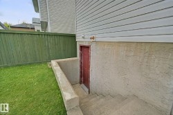 Exterior with concrete basement access and red door - 