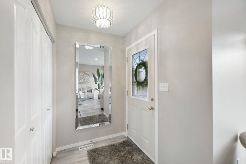 White entryway door with decorative glass inserts, wood-finish flooring, and a decorative ceiling light fixture - 13912 156 Avenue Nw, Edmonton, AB 