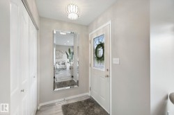 White entryway door with decorative glass inserts, wood-finish flooring, and a decorative ceiling light fixture - 