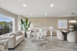 Wood-finish flooring throughout, recessed ceiling lights, large picture window, a secondary window with blinds, and a modern rectangular chandelier - 