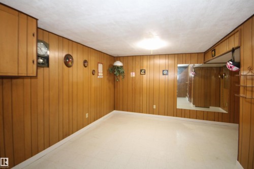 Wood-paneled walls with built-in cabinetry and a large wall mirror - 7743 37 Avenue Nw, Edmonton, AB 