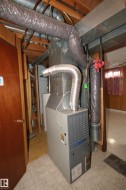 Central HVAC unit with exposed ductwork and wood ceiling joists - 