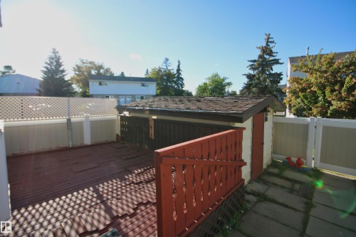 Wood deck with privacy fencing, red painted railing, and a storage shed with a shingle roof - 7743 37 Avenue Nw, Edmonton, AB 