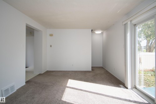 Neutral-toned carpeted flooring, white painted walls, and a sliding glass door - 7743 37 Avenue Nw, Edmonton, AB 