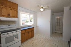 Wood cabinetry with dark countertops, white electric range, bay window, ceiling fan with light fixture, and a glass-paneled door - 