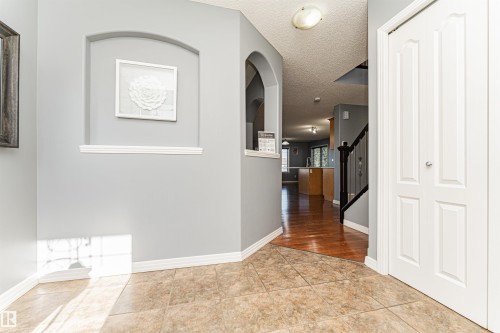 Tiled flooring entryway with an arched wall niche, leading to wood-finish flooring - 1254 Mcallister Way Sw, Edmonton, AB 