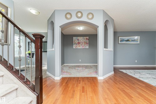 Hardwood flooring, carpeted staircase with wood and metal railing, arched doorways, and recessed lighting - 1254 Mcallister Way Sw, Edmonton, AB 