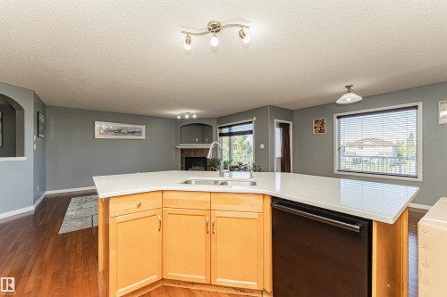 Kitchen island with light wood-finish cabinetry, integrated sink, and white countertop - 1254 Mcallister Way Sw, Edmonton, AB 