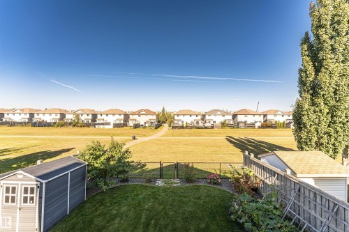 Expansive backyard featuring a manicured lawn, secure fencing, and a storage shed - 1254 Mcallister Way Sw, Edmonton, AB 