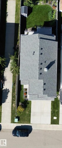 Gable roof with multiple vents and a chimney, concrete driveway and sidewalk, front yard landscaping, and a fenced backyard with a lawn and shed - 1254 Mcallister Way Sw, Edmonton, AB 