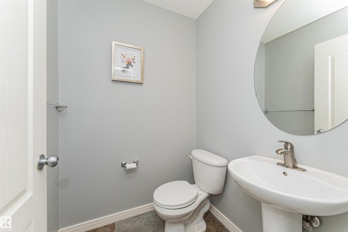 Pedestal sink with a single-handle faucet, circular wall mirror, and neutral wall paint - 1254 Mcallister Way Sw, Edmonton, AB 