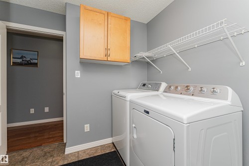 Laundry area with wood-finish cabinetry and overhead wire shelving - 1254 Mcallister Way Sw, Edmonton, AB 