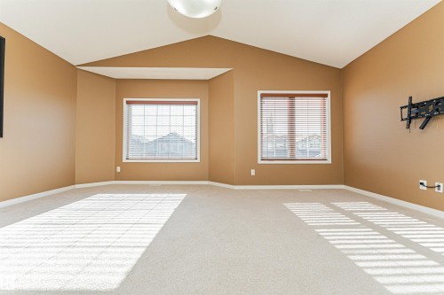 Vaulted ceiling, two windows with blinds, light-colored carpet flooring, ceiling-mounted light fixture, wall-mounted electrical outlets - 1254 Mcallister Way Sw, Edmonton, AB 