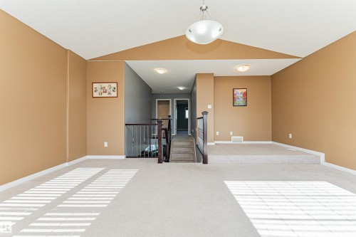 Carpeted loft area featuring a raised platform, wood banister with metal spindles, and recessed lighting - 1254 Mcallister Way Sw, Edmonton, AB 