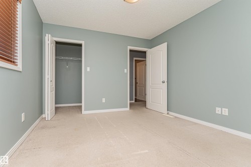 Wall-to-wall carpeting, light blue wall paint, white trim, and a built-in closet with wire shelving - 1254 Mcallister Way Sw, Edmonton, AB 