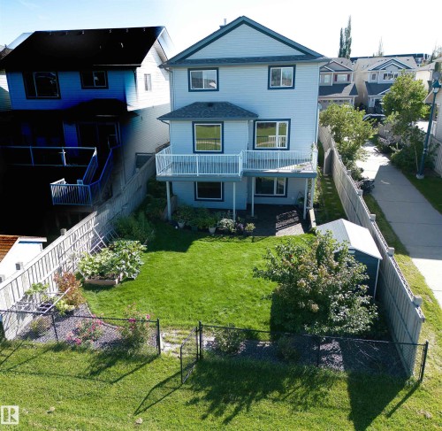 Two-story residence with a light blue siding exterior, a white-railed deck, and a lower-level patio - 1254 Mcallister Way Sw, Edmonton, AB 