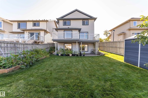 Expansive backyard featuring a manicured lawn, raised garden beds, and a storage shed - 1254 Mcallister Way Sw, Edmonton, AB 