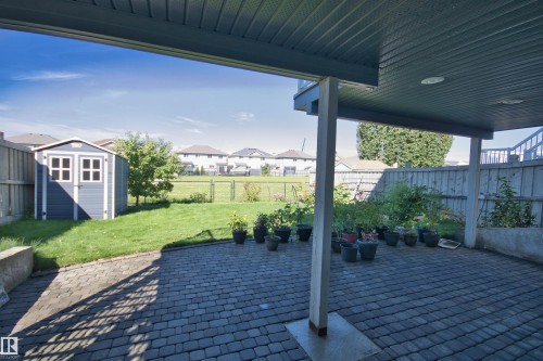 Expansive paver patio with covered overhead structure, featuring recessed lighting and concrete support pillars - 1254 Mcallister Way Sw, Edmonton, AB 