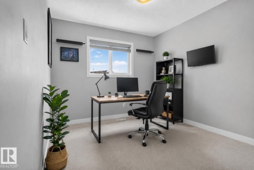 Neutral-toned wall paint and carpeting, natural light from a window, and a flush-mount ceiling light fixture - 319 Desrochers Boulevard Sw, Edmonton, AB 