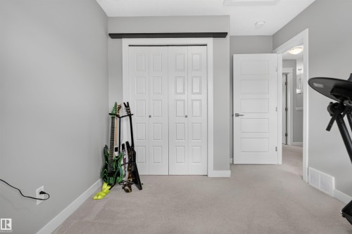 Neutral wall color, light-toned carpeting, panel bi-fold closet doors, and a paneled interior door with modern hardware - 319 Desrochers Boulevard Sw, Edmonton, AB 