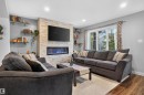 Stone veneer fireplace with an electric insert, recessed lighting, wood-finish flooring, and built-in glass shelving - 319 Desrochers Boulevard Sw, Edmonton, AB 