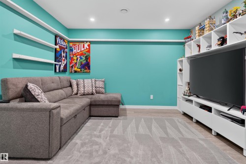 Built-in shelving, wall-mounted display shelves, recessed lighting, wood-finish flooring, and a large area rug - 319 Desrochers Boulevard Sw, Edmonton, AB 