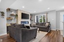 Stacked stone fireplace with a linear insert, wood-finish flooring, recessed lighting, and a multi-pane window - 319 Desrochers Boulevard Sw, Edmonton, AB 