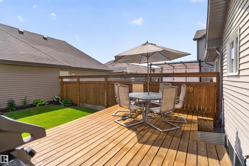 Expansive wood deck with a privacy fence, manicured lawn, and garden beds - 319 Desrochers Boulevard Sw, Edmonton, AB 